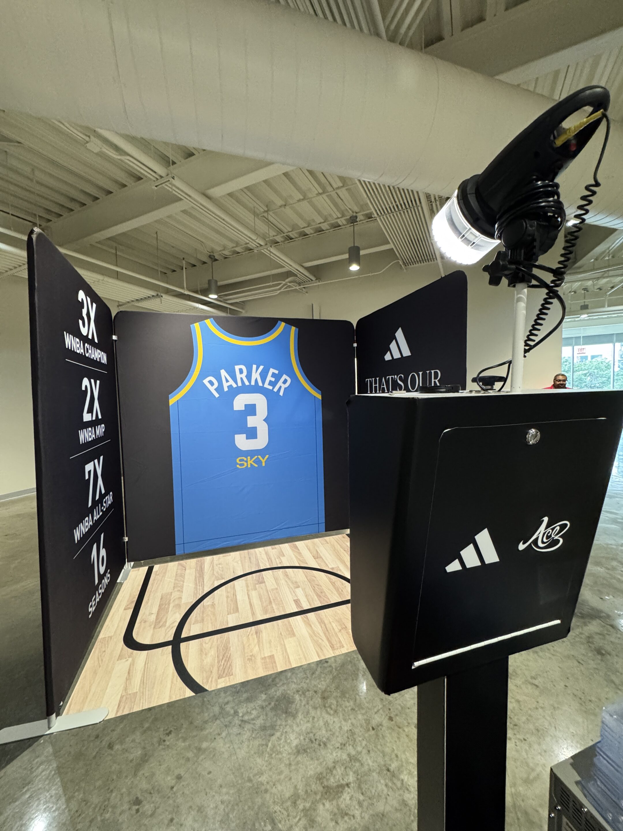 A blue Chicago Sky basketball jersey with Parker 3 is displayed in an indoor exhibit, perfect for a Brand Activation Photo Booth and featuring Adidas branding and WNBA stats on the side panels.